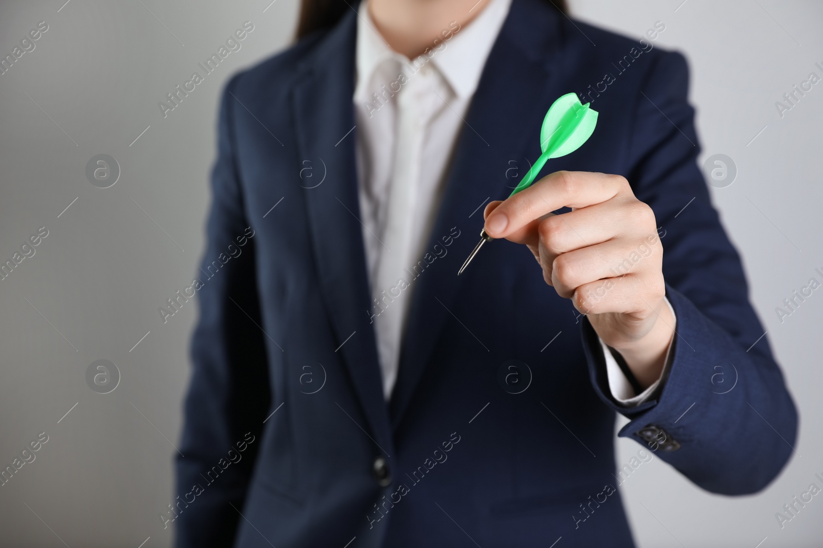 Photo of Businesswoman holding green dart on light background, closeup