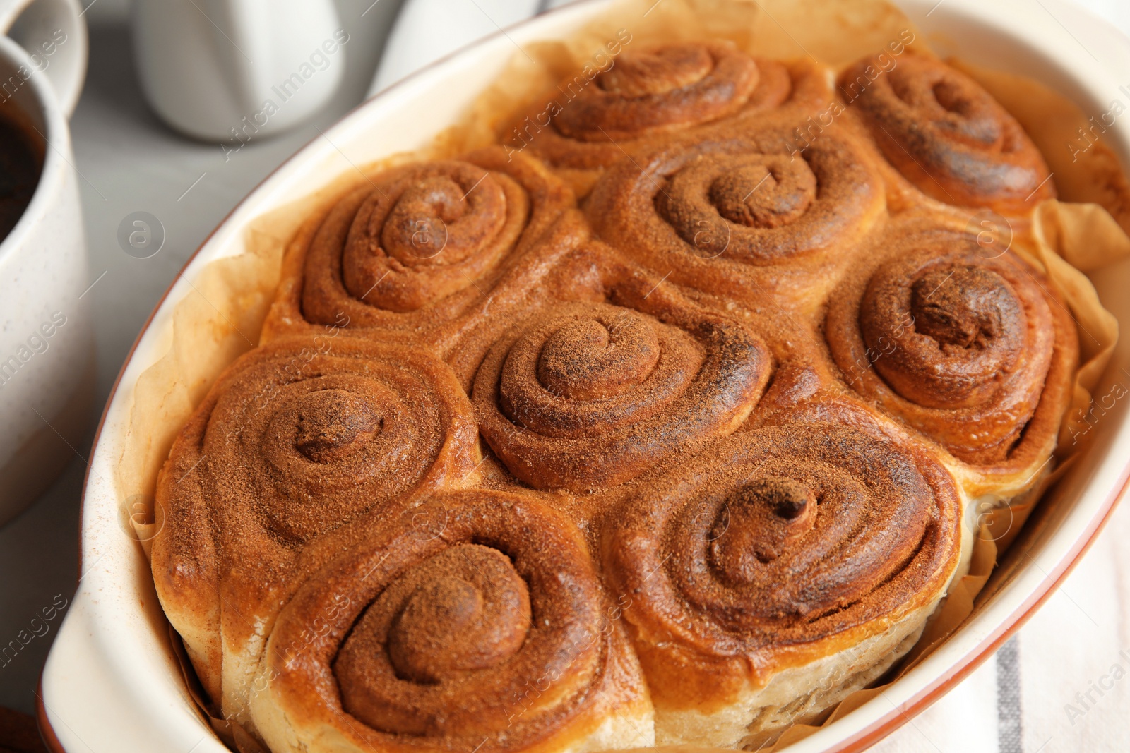 Photo of Baking dish with cinnamon rolls on table, closeup