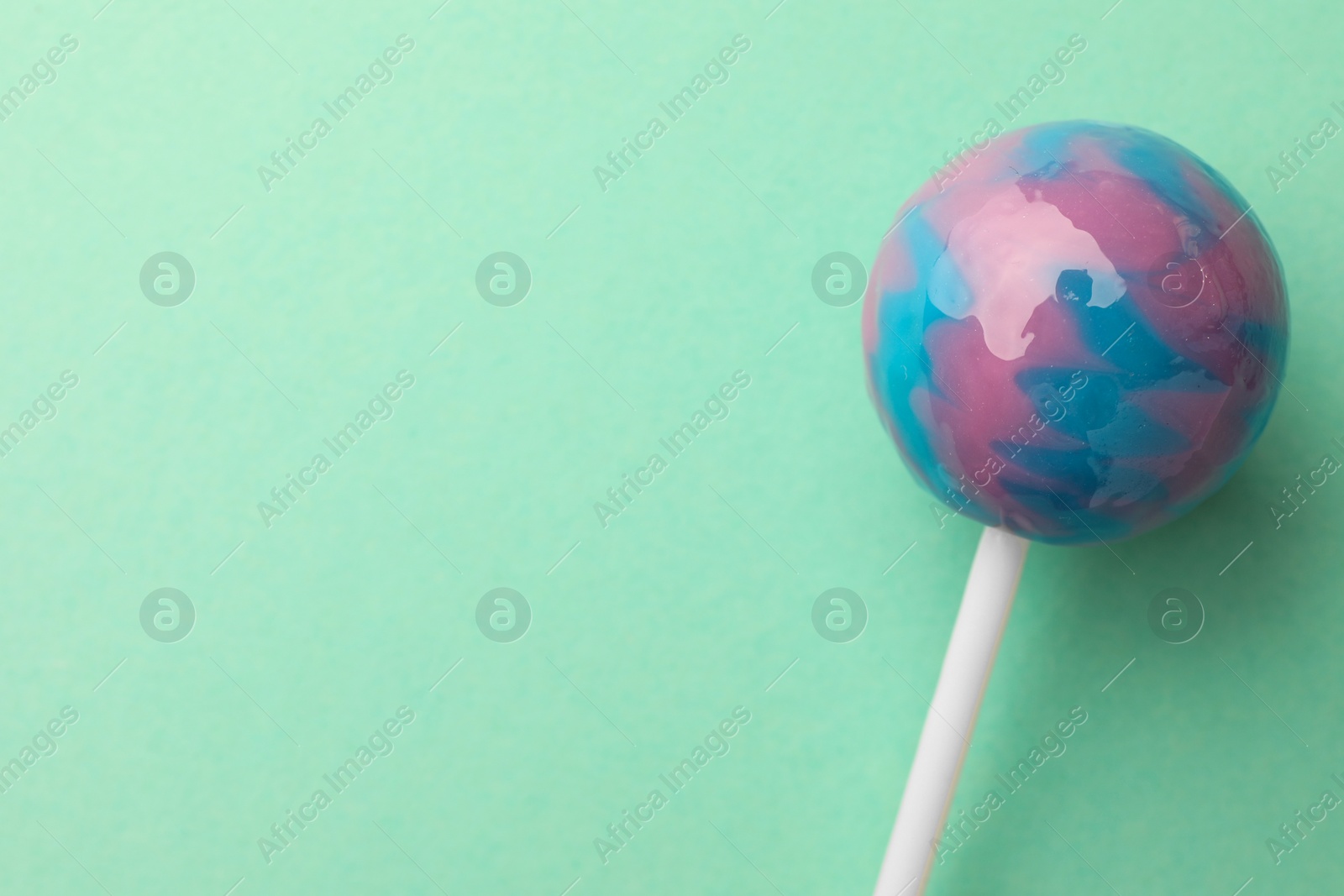 Photo of Tasty lollipop on turquoise background, top view. Space for text