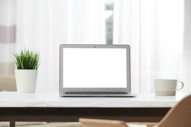 Laptop with blank screen on table indoors. Space for text