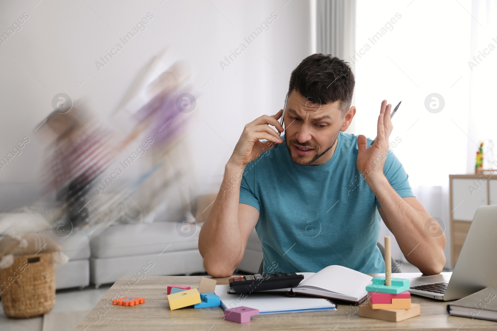 Image of Children disturbing overwhelmed man in living room. Working from home during quarantine