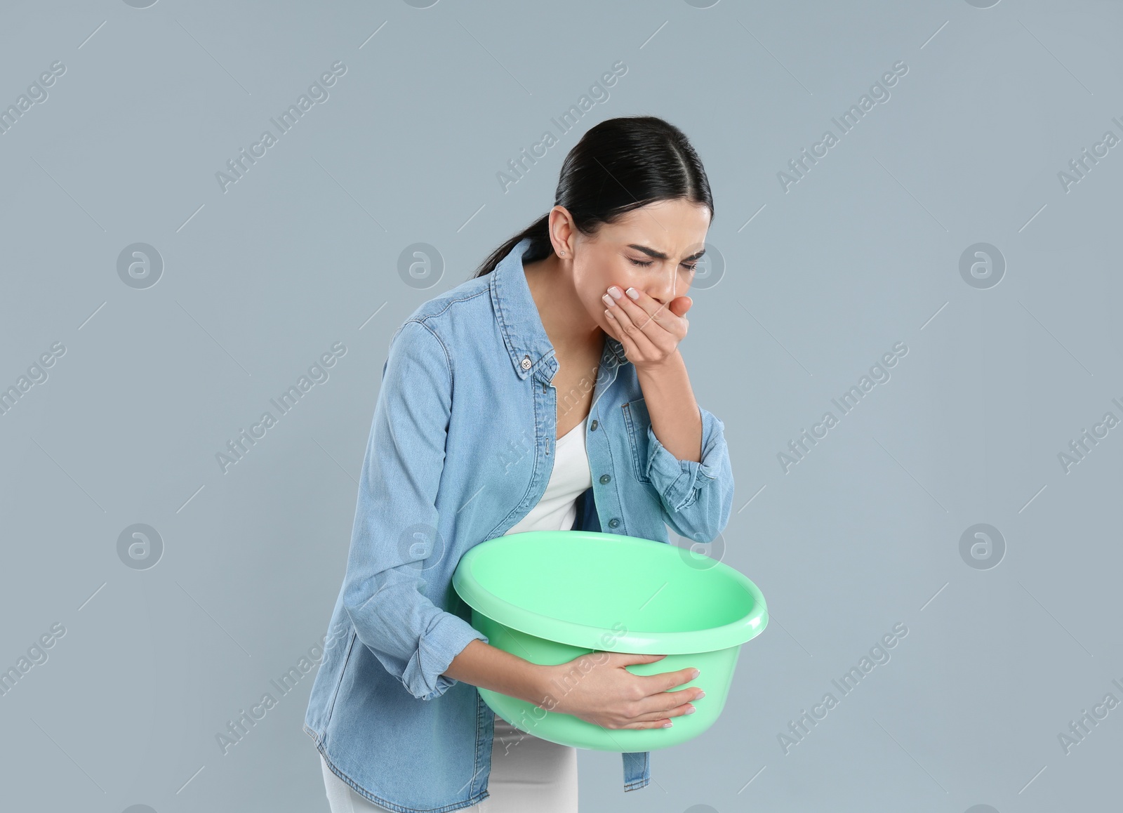 Photo of Woman with basin suffering from nausea on grey background. Food poisoning