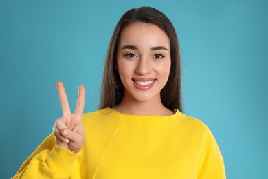Photo of Woman showing number two with her hand on light blue background