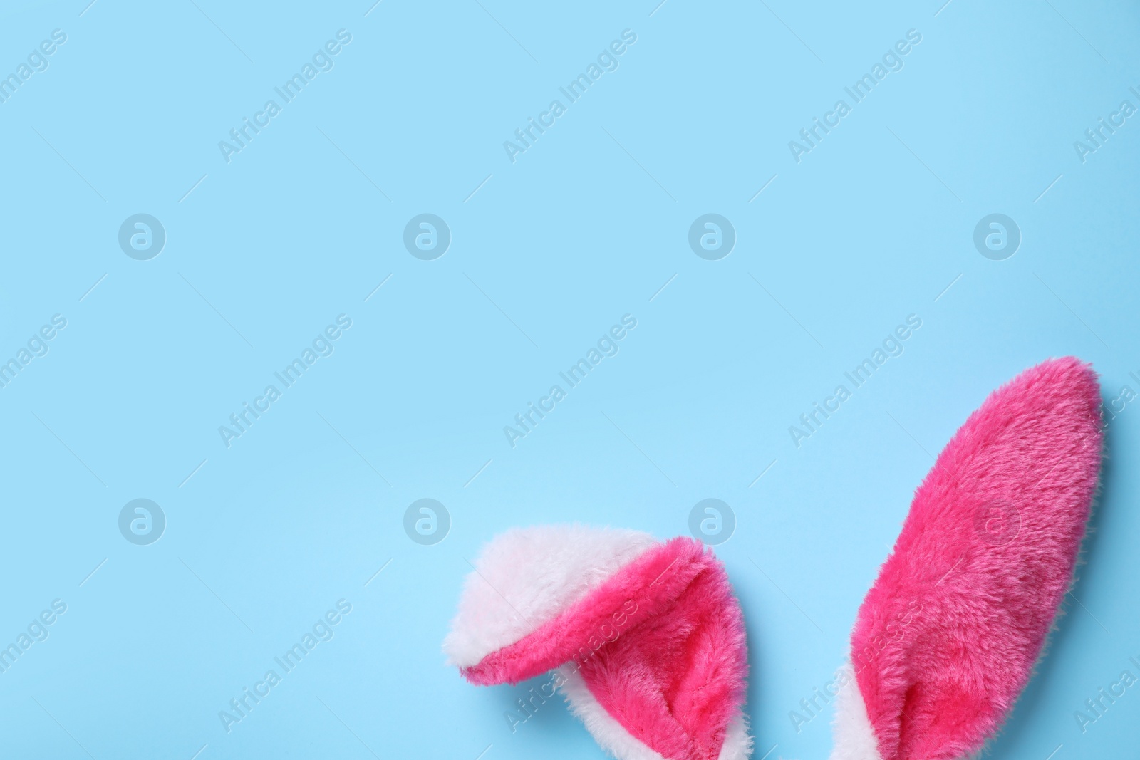 Photo of Decorative bunny ears and space for text on light blue background, flat lay. Easter holiday