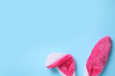 Photo of Decorative bunny ears and space for text on light blue background, flat lay. Easter holiday