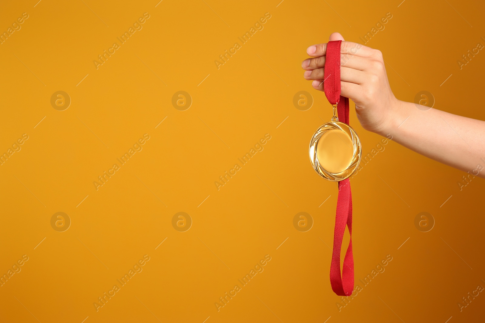 Photo of Woman holding gold medal on yellow background, closeup. Space for text