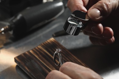 Photo of Professional jeweler working with ring at table, closeup