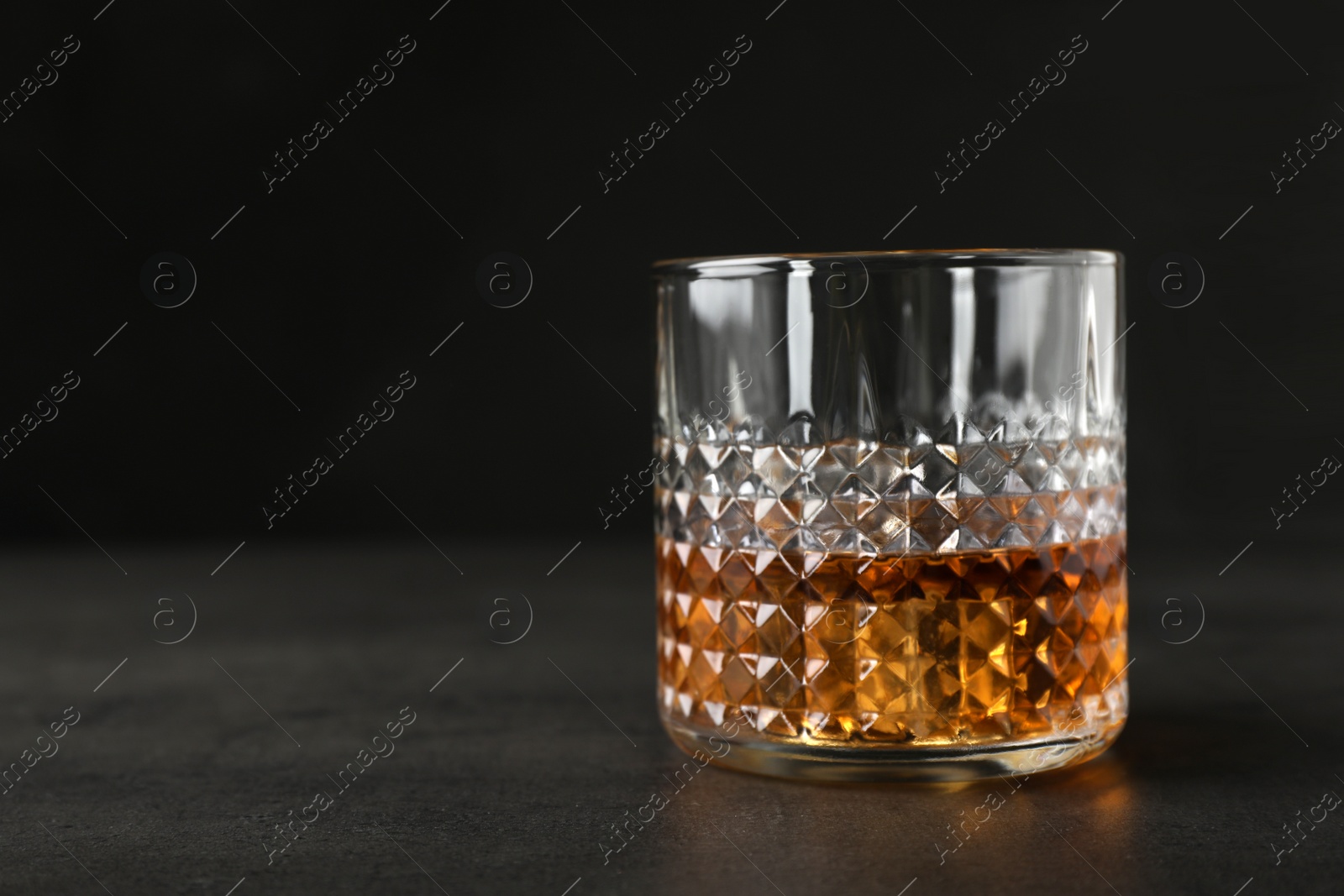 Photo of Golden whiskey in glass with ice cubes on table. Space for text