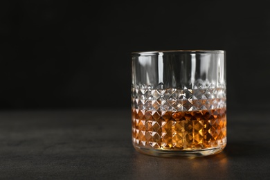 Photo of Golden whiskey in glass with ice cubes on table. Space for text