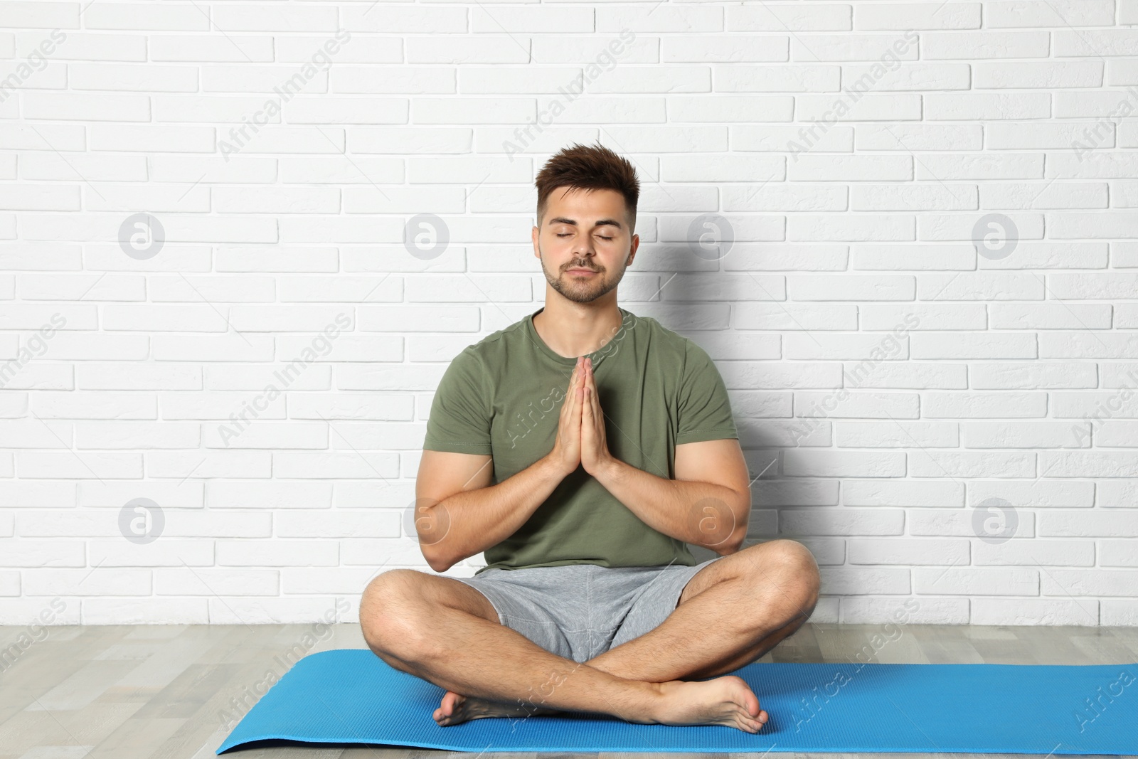 Photo of Young man practicing zen yoga near white brick wall