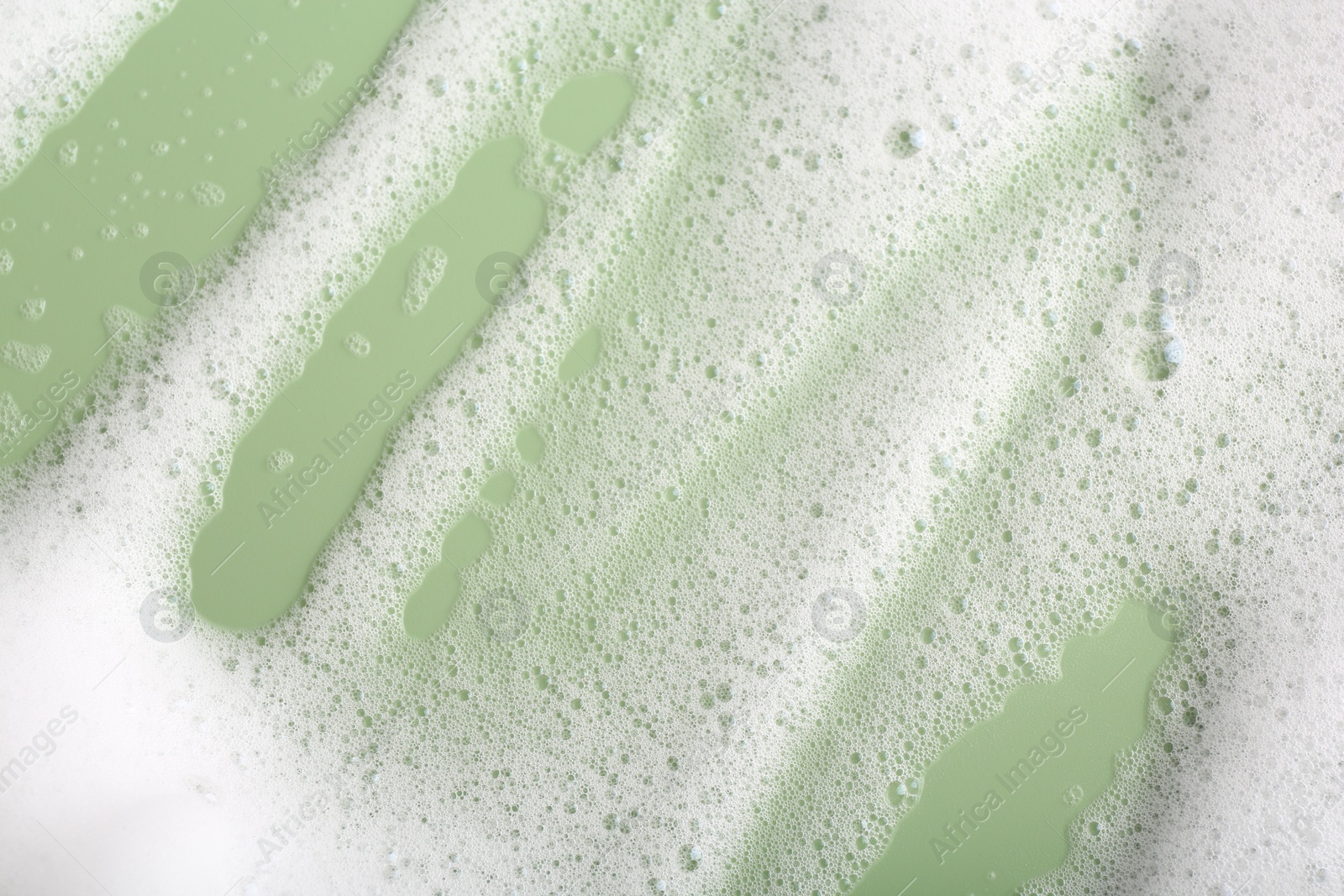 Photo of White fluffy foam on green background, top view