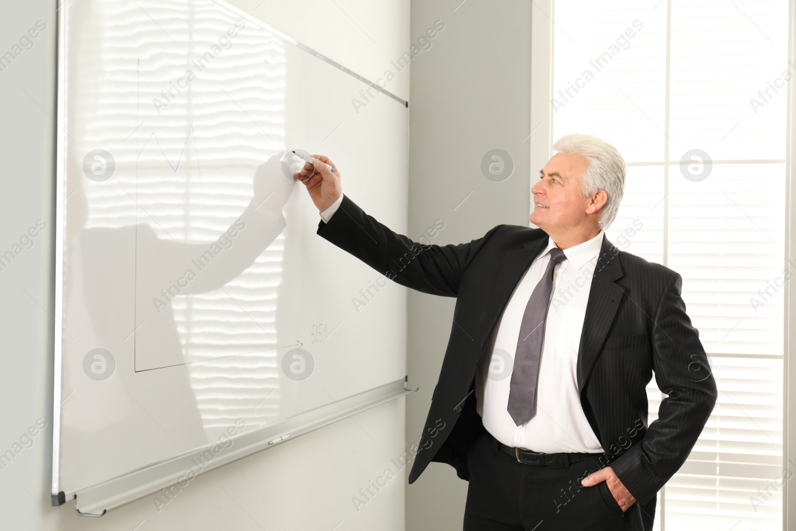 Photo of Senior business trainer near whiteboard in office