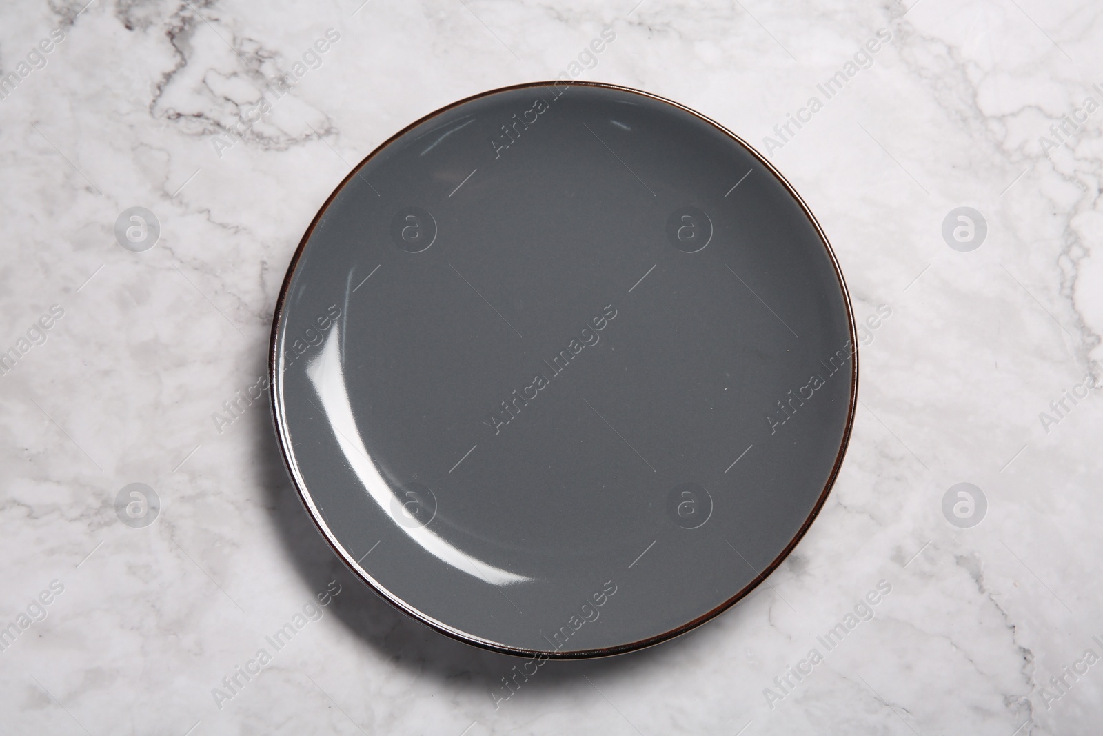 Photo of One grey ceramic plate on white marble table, top view