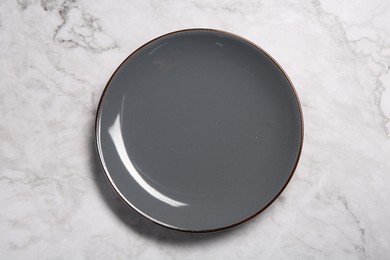 One grey ceramic plate on white marble table, top view