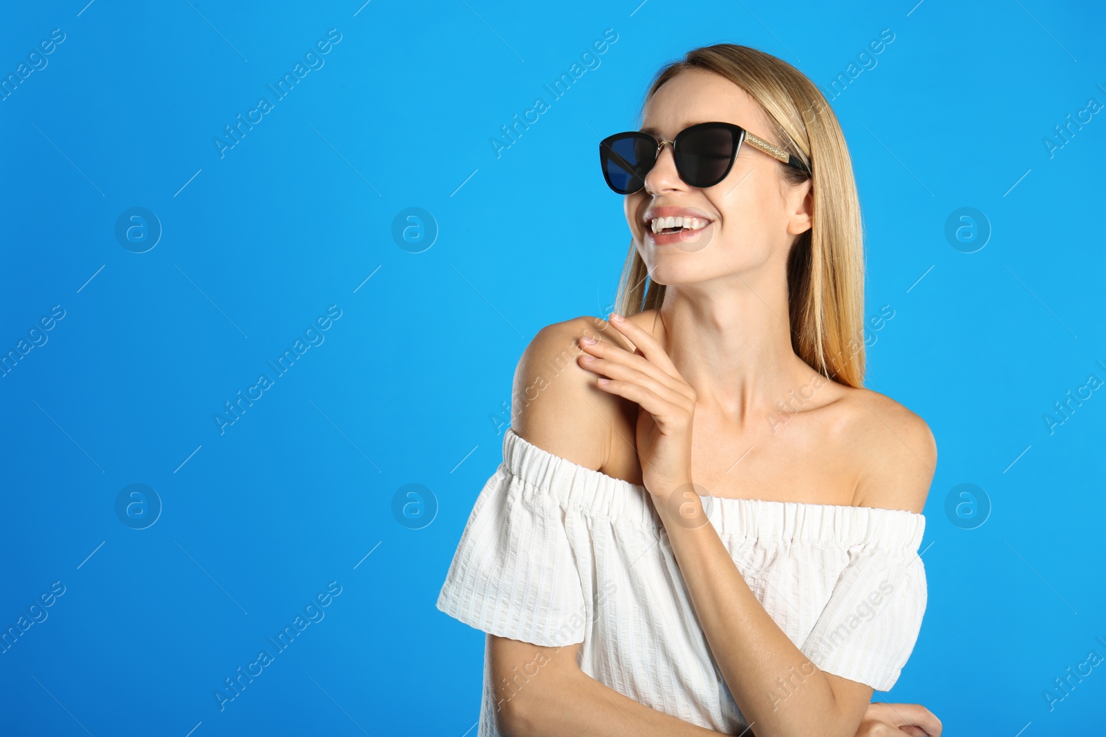 Photo of Beautiful woman in stylish sunglasses on light blue background, space for text