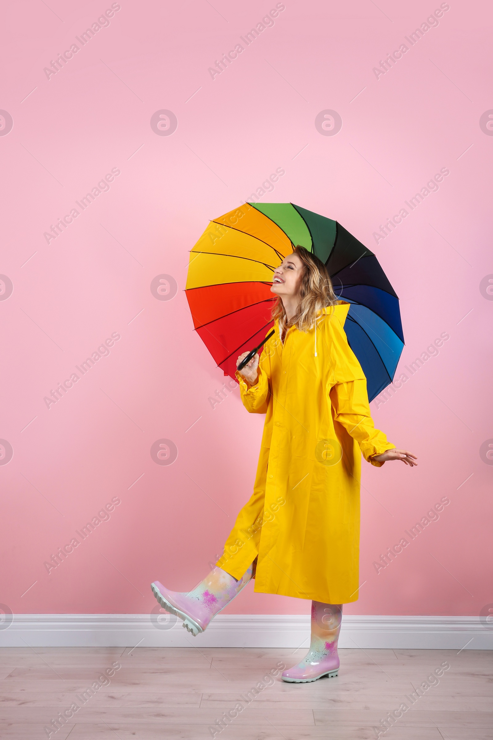 Photo of Woman with rainbow umbrella near color wall