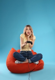 Photo of Emotional young woman playing video games with controller on color background. Space for text