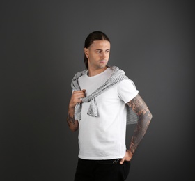 Photo of Young man with stylish tattoos on grey background. Space for text