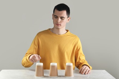 Man playing shell game at light marble table