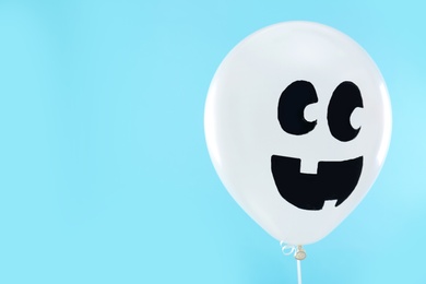 White balloon with drawing of happy face on blue background, space for text. Halloween party