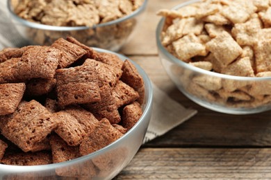 Photo of Different breakfast cereals in glass bowls on wooden table, closeup