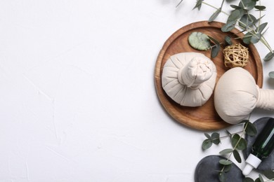 Photo of Flat lay composition with herbal massage bags, spa products and eucalyptus branches on white table. Space for text