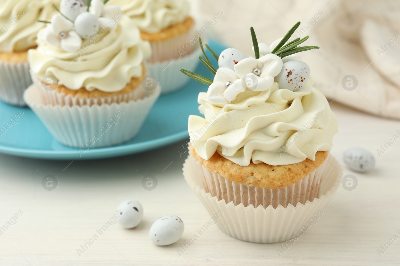 Photo of Tasty Easter cupcakes with vanilla cream on light wooden table, closeup