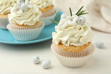 Photo of Tasty Easter cupcakes with vanilla cream on light wooden table, closeup