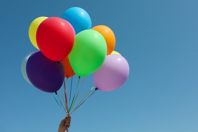 Photo of Woman with bunch of colorful balloons against blue sky, closeup. Space for text