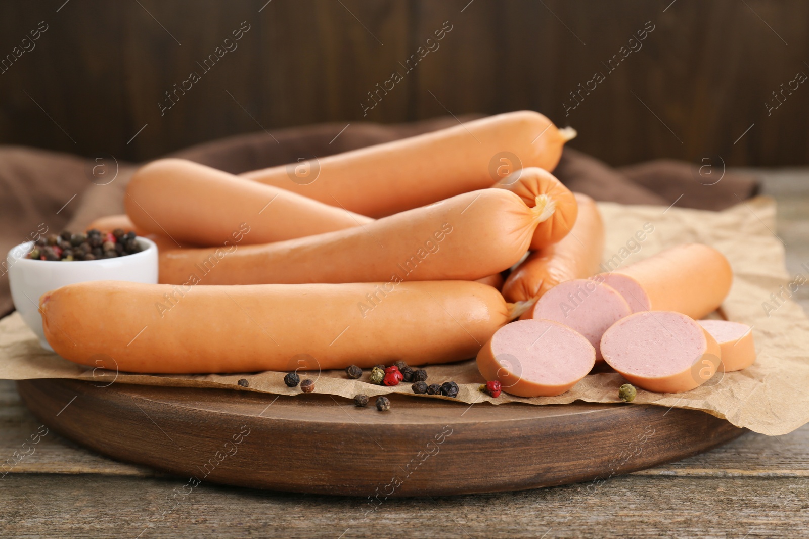 Photo of Tasty sausages and peppercorns on wooden table, closeup. Meat product