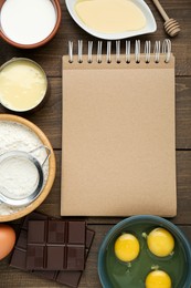 Blank recipe book and different ingredients on wooden table, flat lay. Space for text