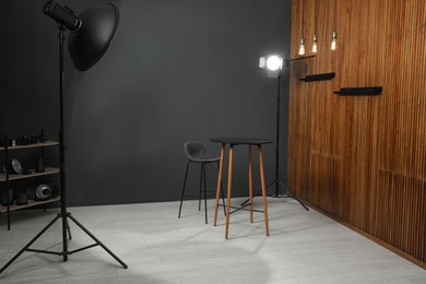 Photo of Empty table with chair and professional equipment in photographer's studio