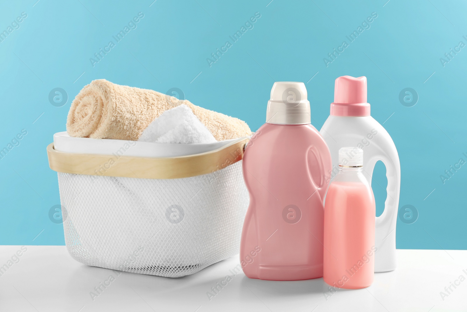 Photo of Bottles of laundry detergents and towels on white table