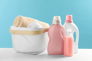 Bottles of laundry detergents and towels on white table