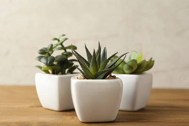 Artificial plants in white flower pots on wooden table