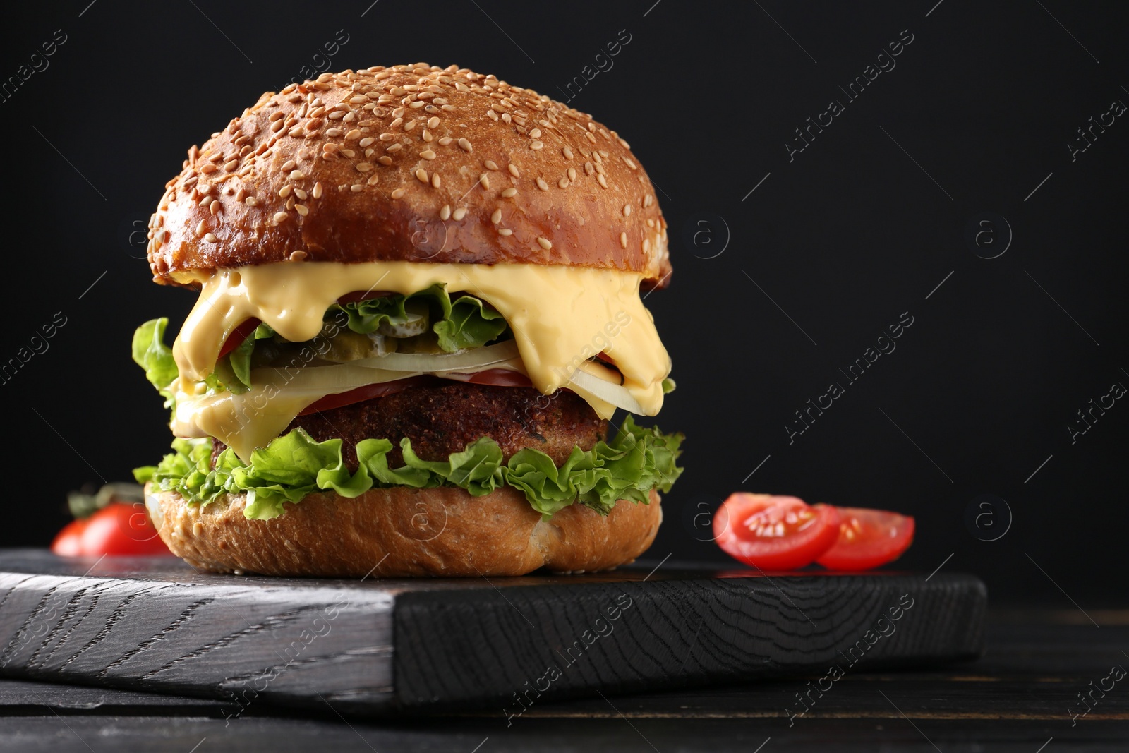 Photo of Vegetarian burger with delicious patty on black wooden table, closeup. Space for text