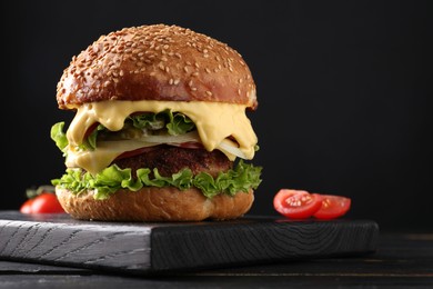 Vegetarian burger with delicious patty on black wooden table, closeup. Space for text