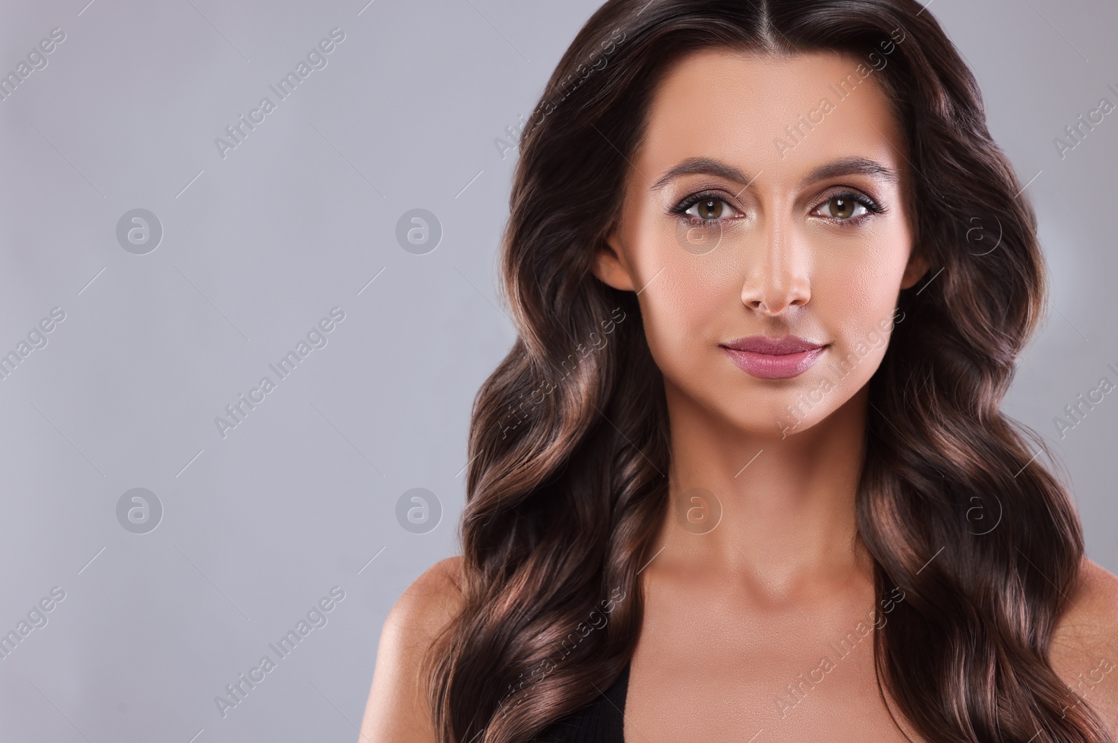 Image of Gorgeous woman with shiny wavy hair on grey background, space for text. Professional hairstyling
