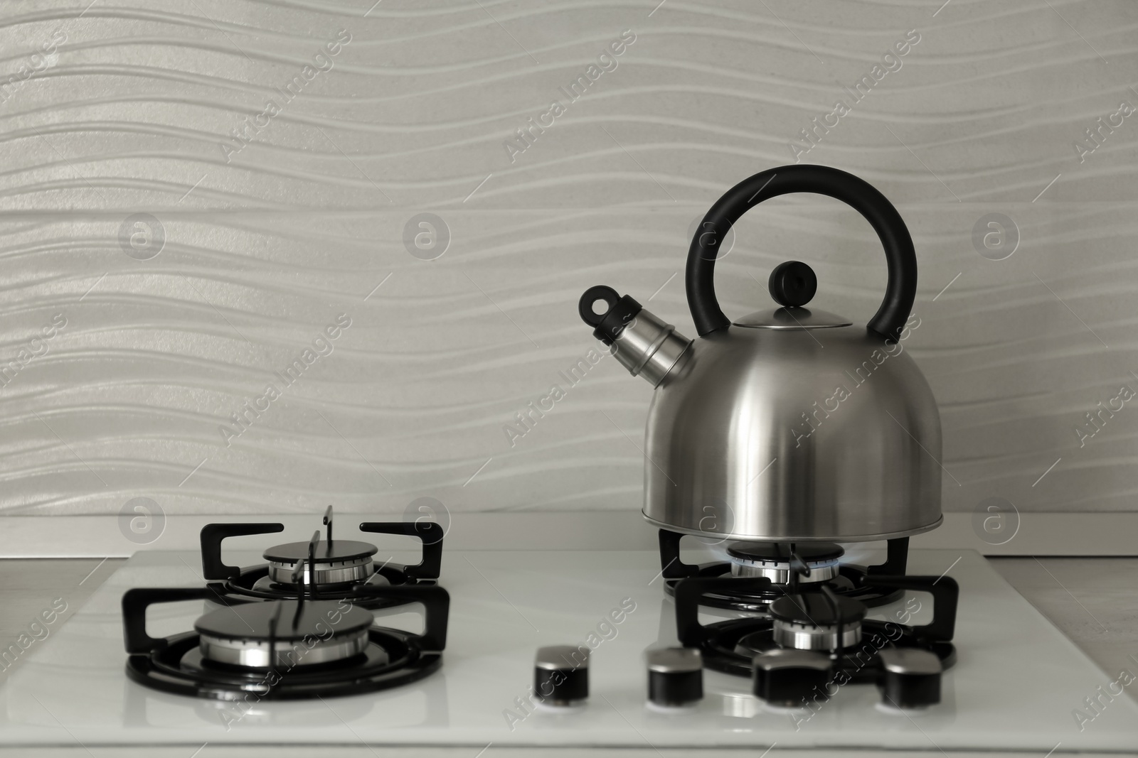 Photo of Steel kettle with whistle on modern gas stove. Space for text