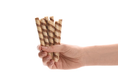 Woman holding tasty wafer roll sticks on white background, closeup. Crispy food