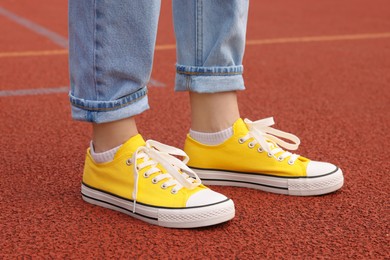 Photo of Woman wearing yellow classic old school sneakers on court outdoors, closeup