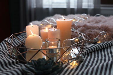 Photo of Tray with burning candles on striped fabric