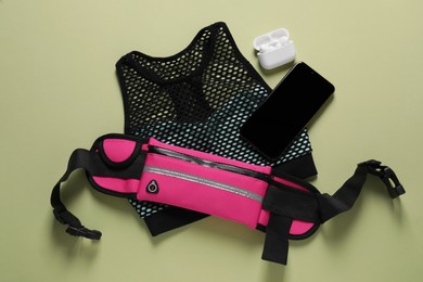 Photo of Flat lay composition with stylish pink waist bag on pale green background
