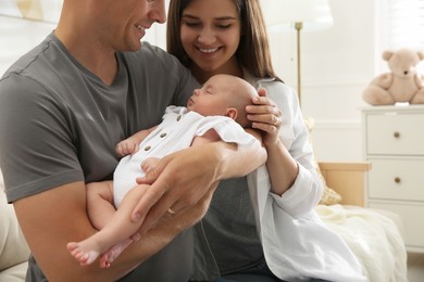 Photo of Happy couple holding their sleeping baby at home, closeup