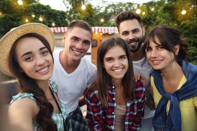 Happy friends taking selfie near motorhome. Camping season