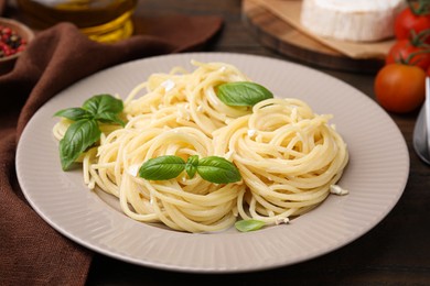 Delicious pasta with brie cheese and basil leaves on table, closeup
