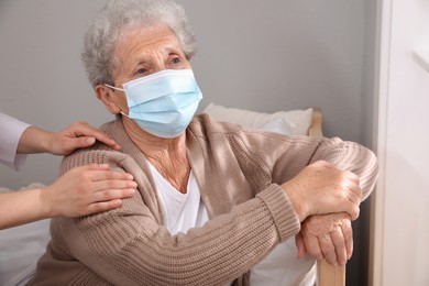 Photo of Doctor taking care of lonely senior woman in protective mask at nursing home