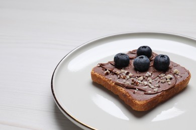 Photo of Toast with tasty nut butter, blueberries and nuts on white wooden table, closeup. Space for text