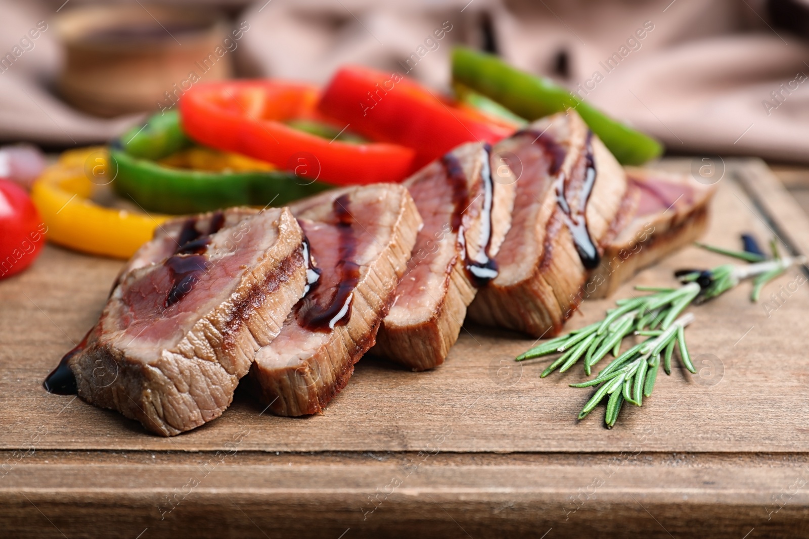 Photo of Cut roasted meat served with sauce and garnish on wooden board, closeup