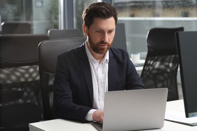 Photo of Man working on laptop at white desk in office